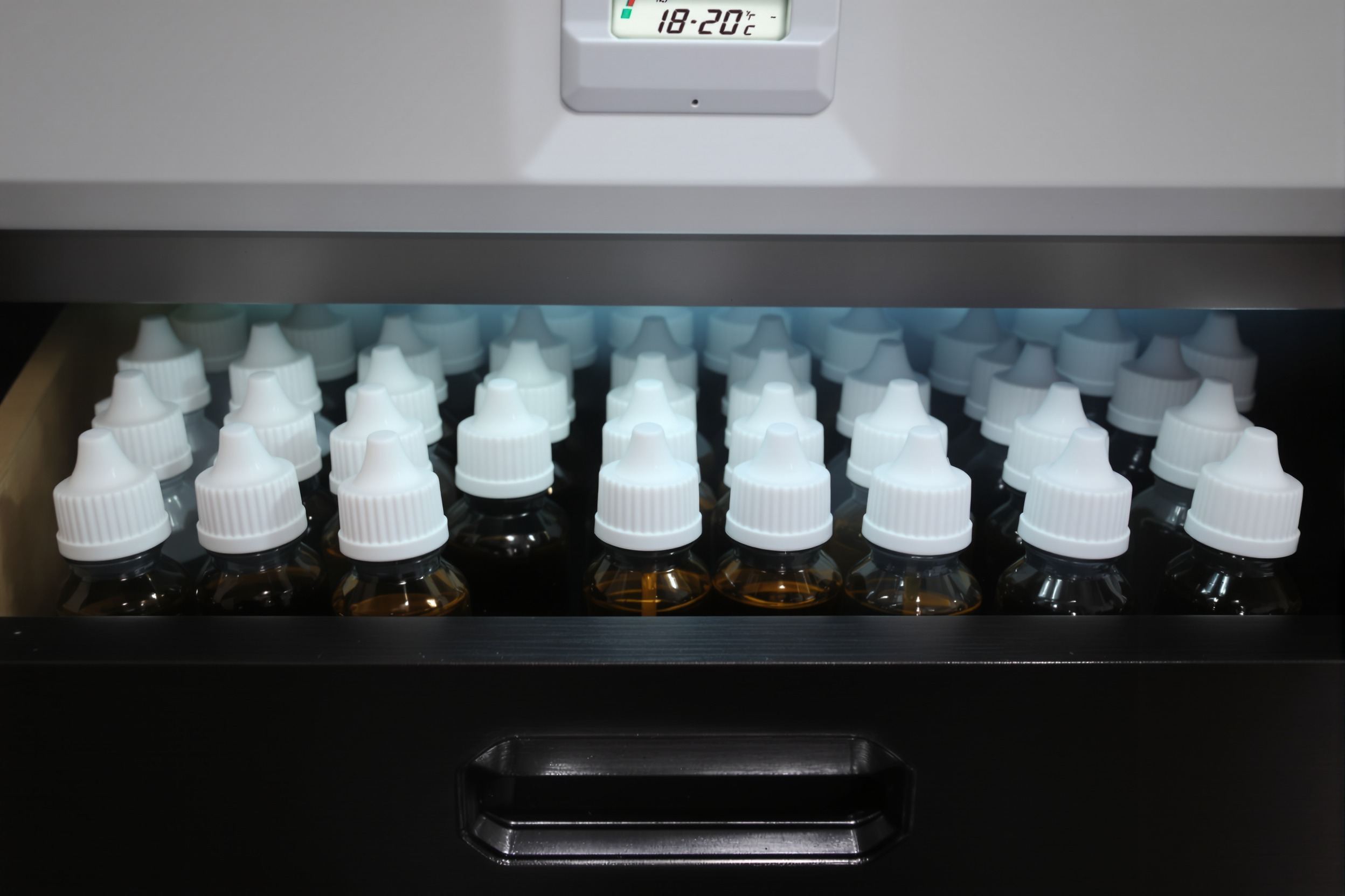 Flacons d'e-liquide rangés debout dans un tiroir sombre